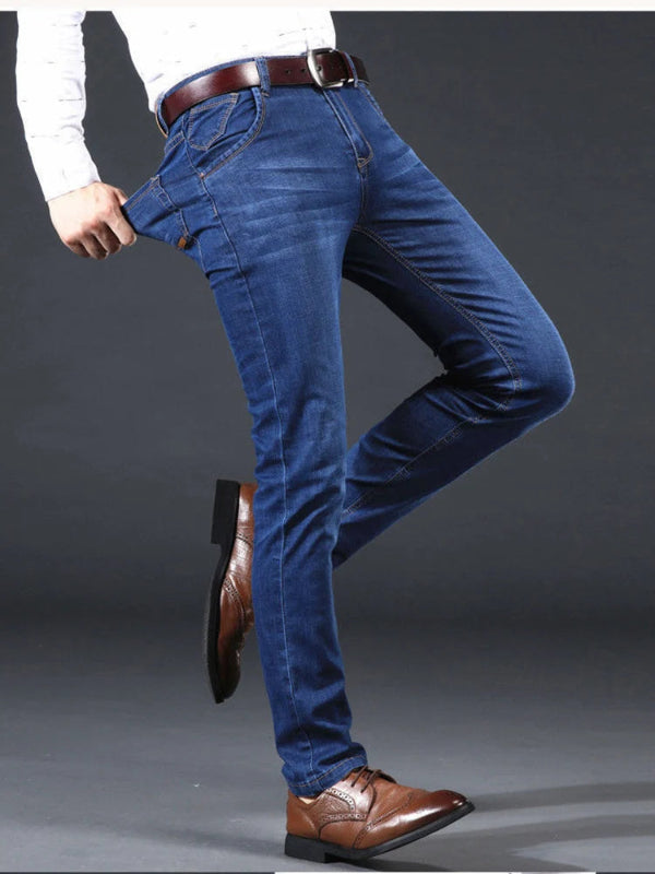Person wearing blue jeans and brown shoes on a gray background