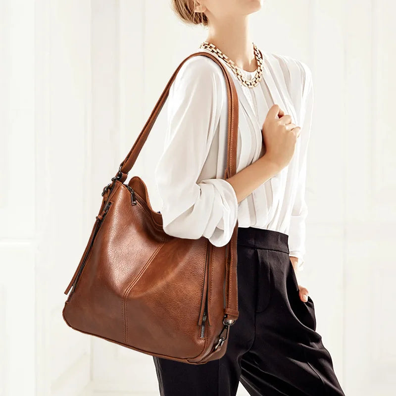 Person holding a brown leather handbag against a white background