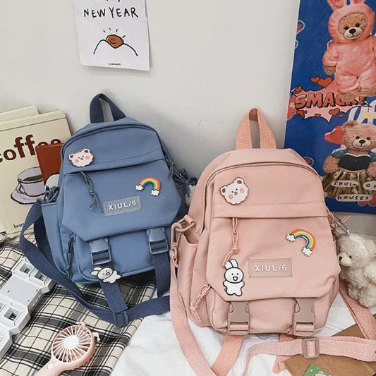 Two backpacks, one blue and one pink, with decorative elements on a casual setting.