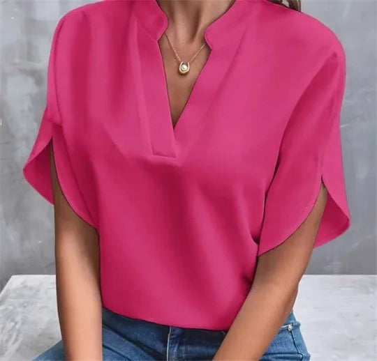 Person wearing a bright pink blouse with a gray background