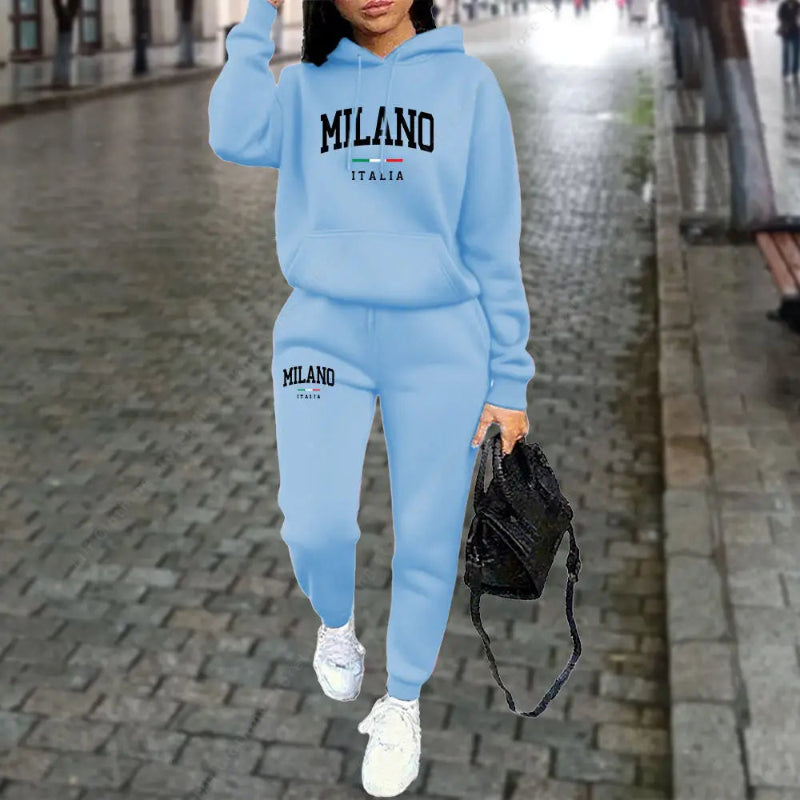 Person wearing a light blue 'Milano Italia' hoodie and pants on a city street.