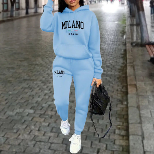 Person wearing a light blue 'Milano Italia' hoodie and pants on a city street.