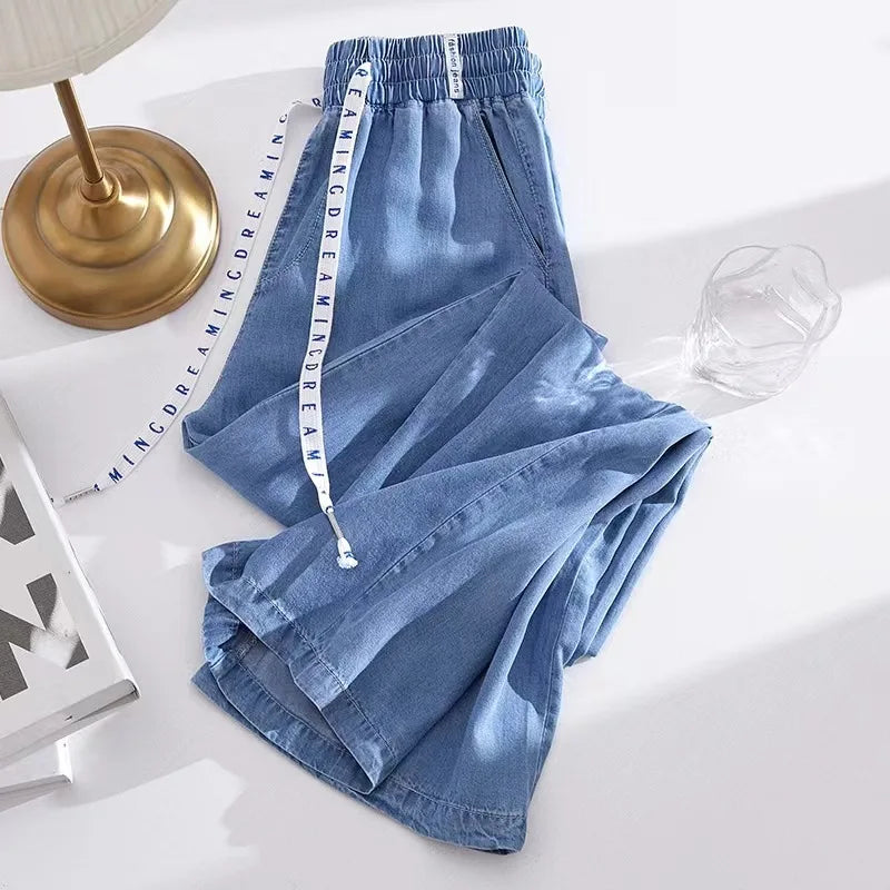 Blue denim pants with a measuring tape on a white surface