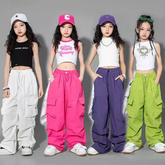Four young women wearing colorful outfits and caps on a gray background