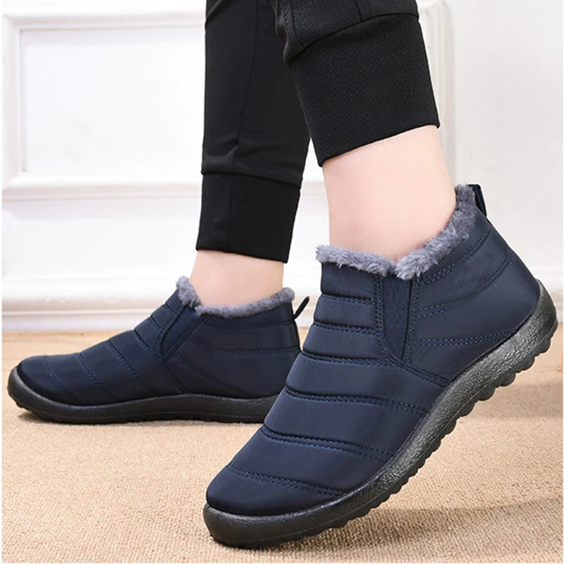 Navy blue winter boots with fur trim worn by a person indoors.