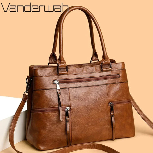 Brown leather handbag with a shoulder strap on a beige background, featuring the Vanderwah brand.
