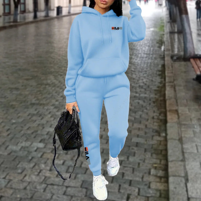 Person wearing a blue tracksuit with a brand logo on a city street.