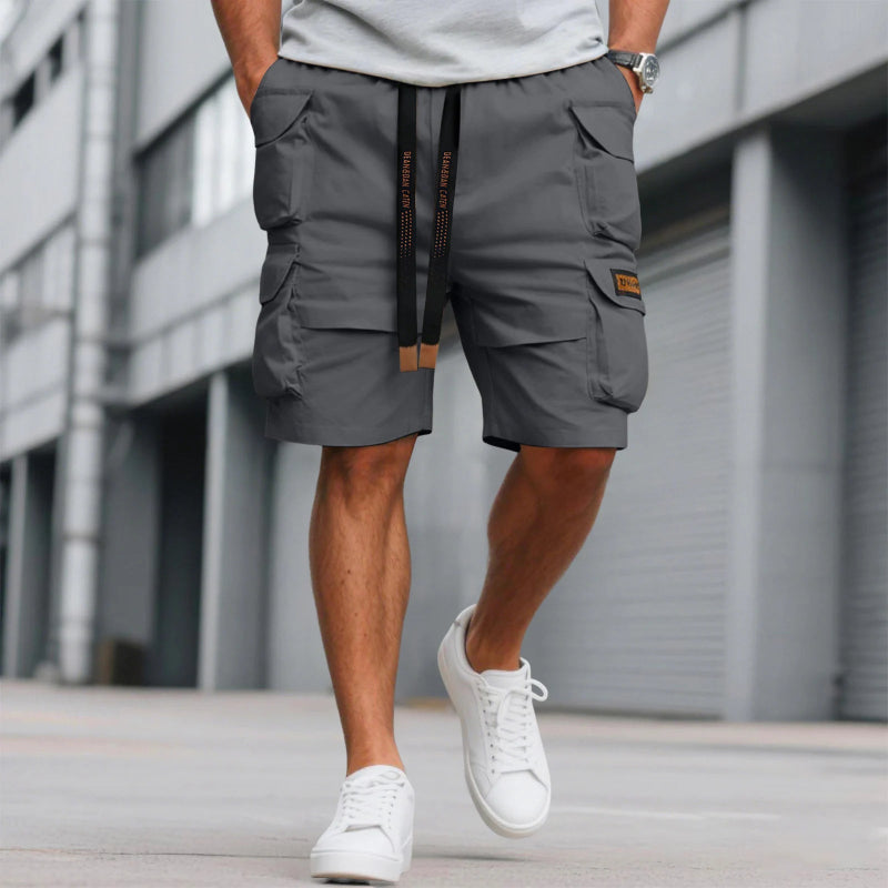 Person wearing gray cargo shorts and white sneakers in front of a building.