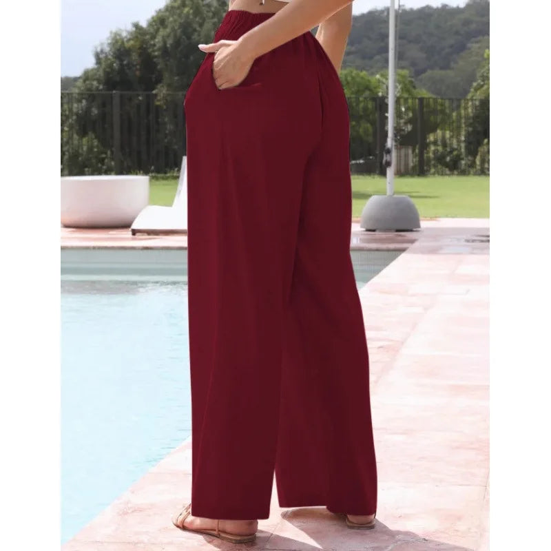 Person wearing burgundy wide-leg pants by a poolside.