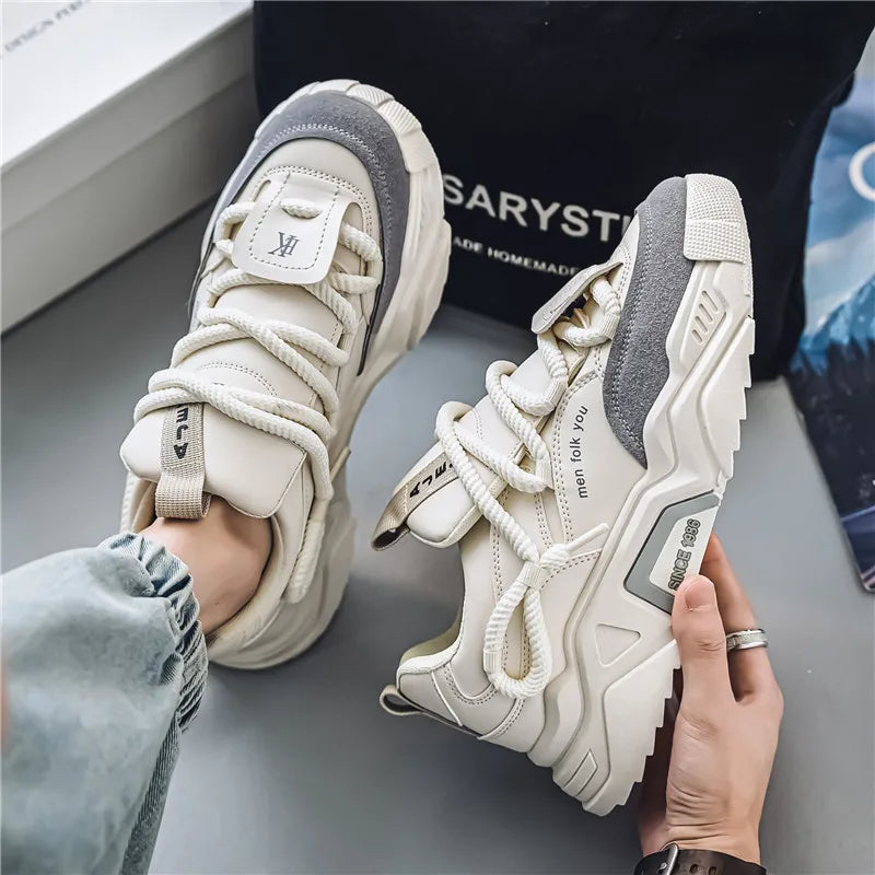 White sneakers with gray accents worn by a person on a gray surface.