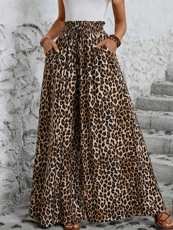 Person wearing a leopard print skirt with a white top against a stone wall.