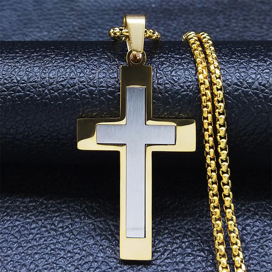 Gold and silver cross pendant with chain on a textured black surface