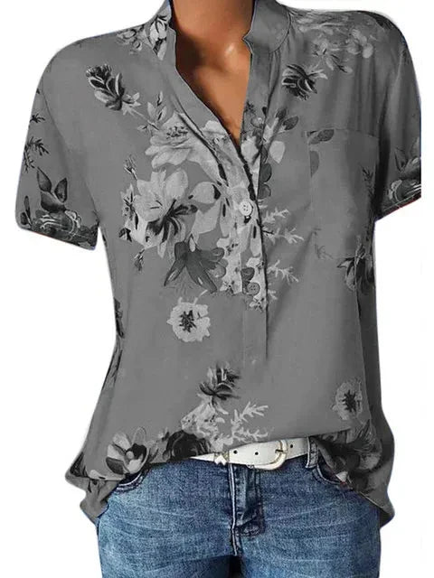 Gray floral blouse worn by a person with blue jeans on a white background