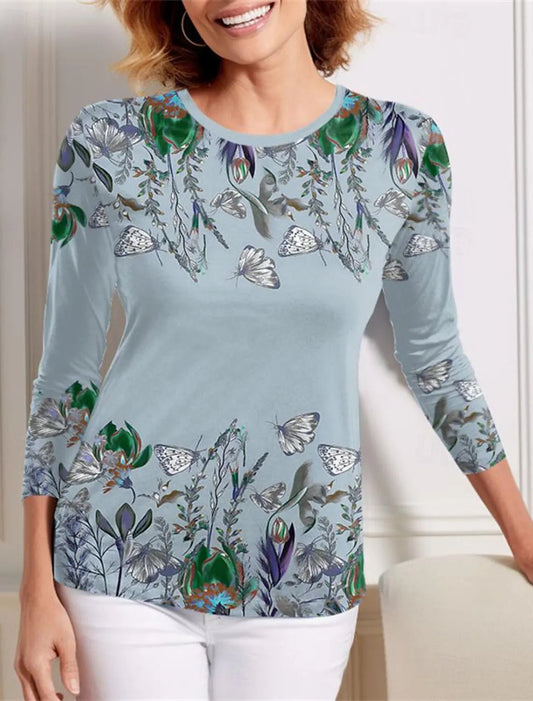 Woman wearing a light blue long-sleeve top with floral and butterfly patterns.