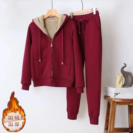 Maroon tracksuit with beige lining on hangers against a white wall.
