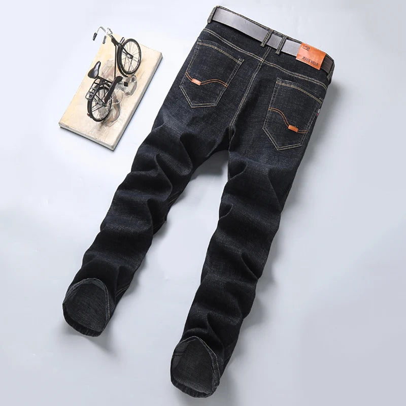 Black jeans with orange stitching on a light gray background