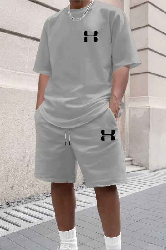 Person wearing a gray Under Armour outfit with brand logos on a stone pavement.