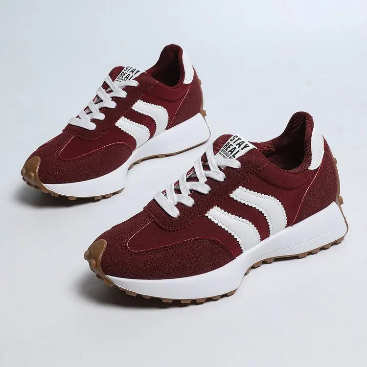 Maroon and white sneakers with a visible brand logo on a light gray background