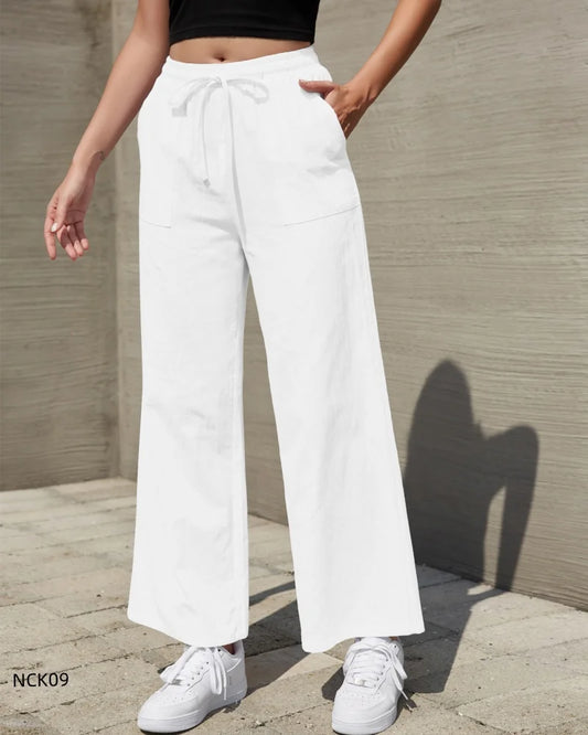Person wearing white pants and white sneakers against a neutral background