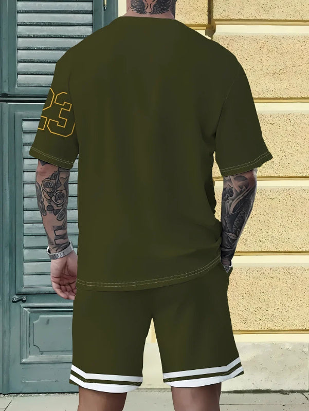 Person wearing a green t-shirt and shorts set with tattoos visible, standing against a textured wall.