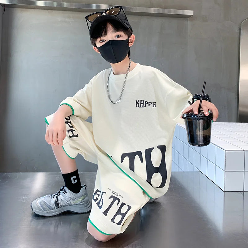 Person wearing a white oversized shirt with text, sitting on a metallic surface.