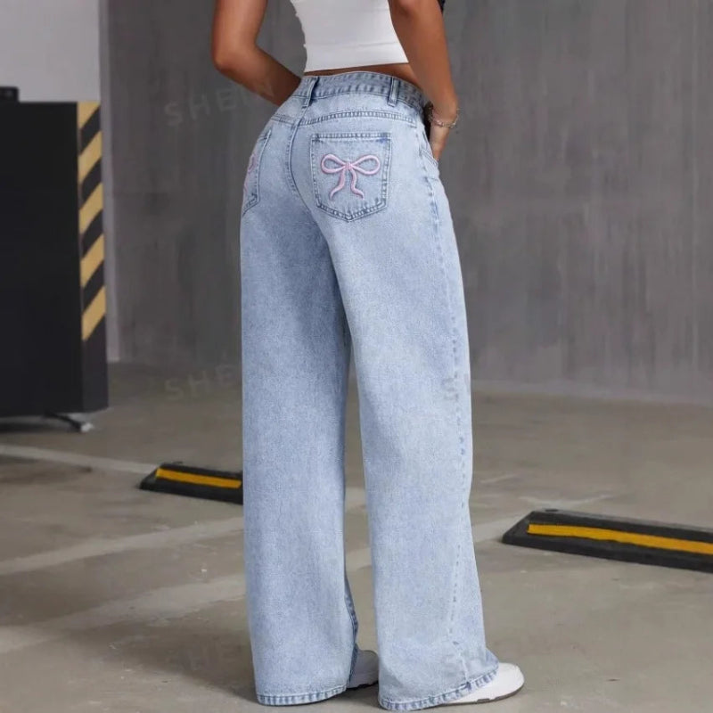 Person wearing light blue jeans with a decorative bow detail in an industrial setting.