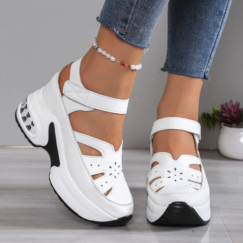 White platform sandals with black soles worn by a person on a neutral background