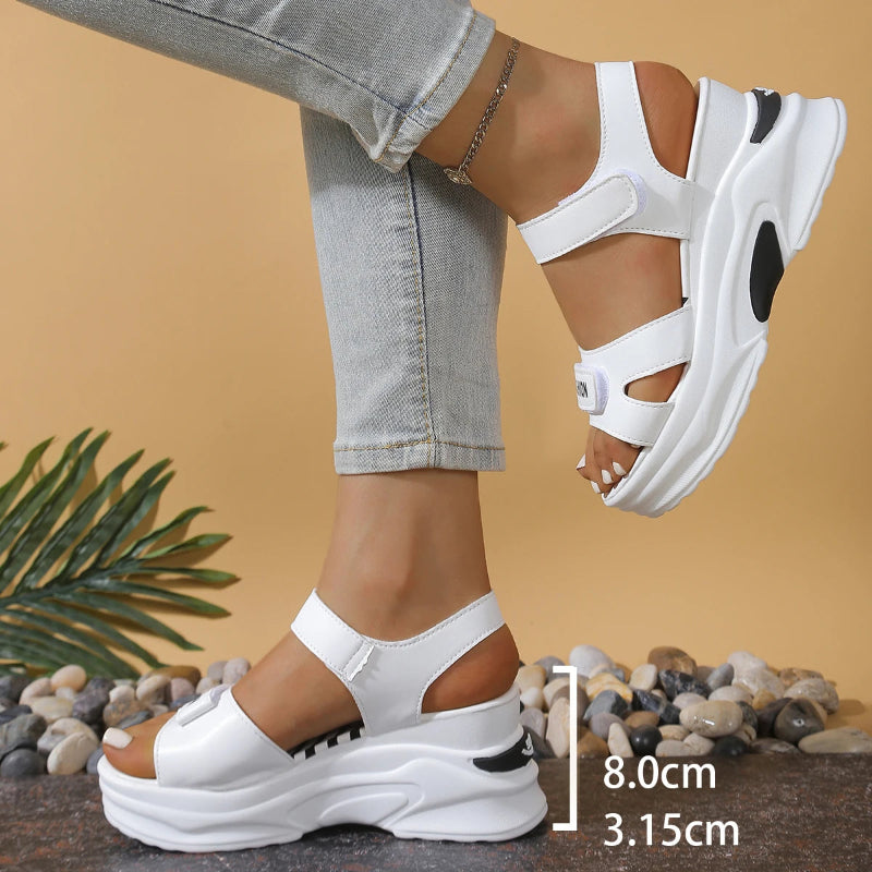 White platform sandals worn with light gray jeans on a beige background