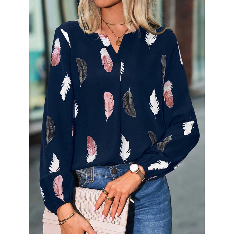 Woman wearing a navy blue blouse with feather pattern, holding a clutch.