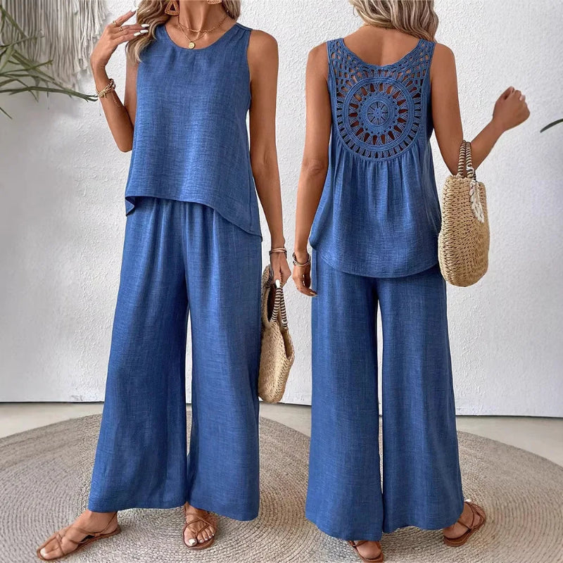 Woman wearing a blue sleeveless top and wide-leg pants, holding a straw bag.
