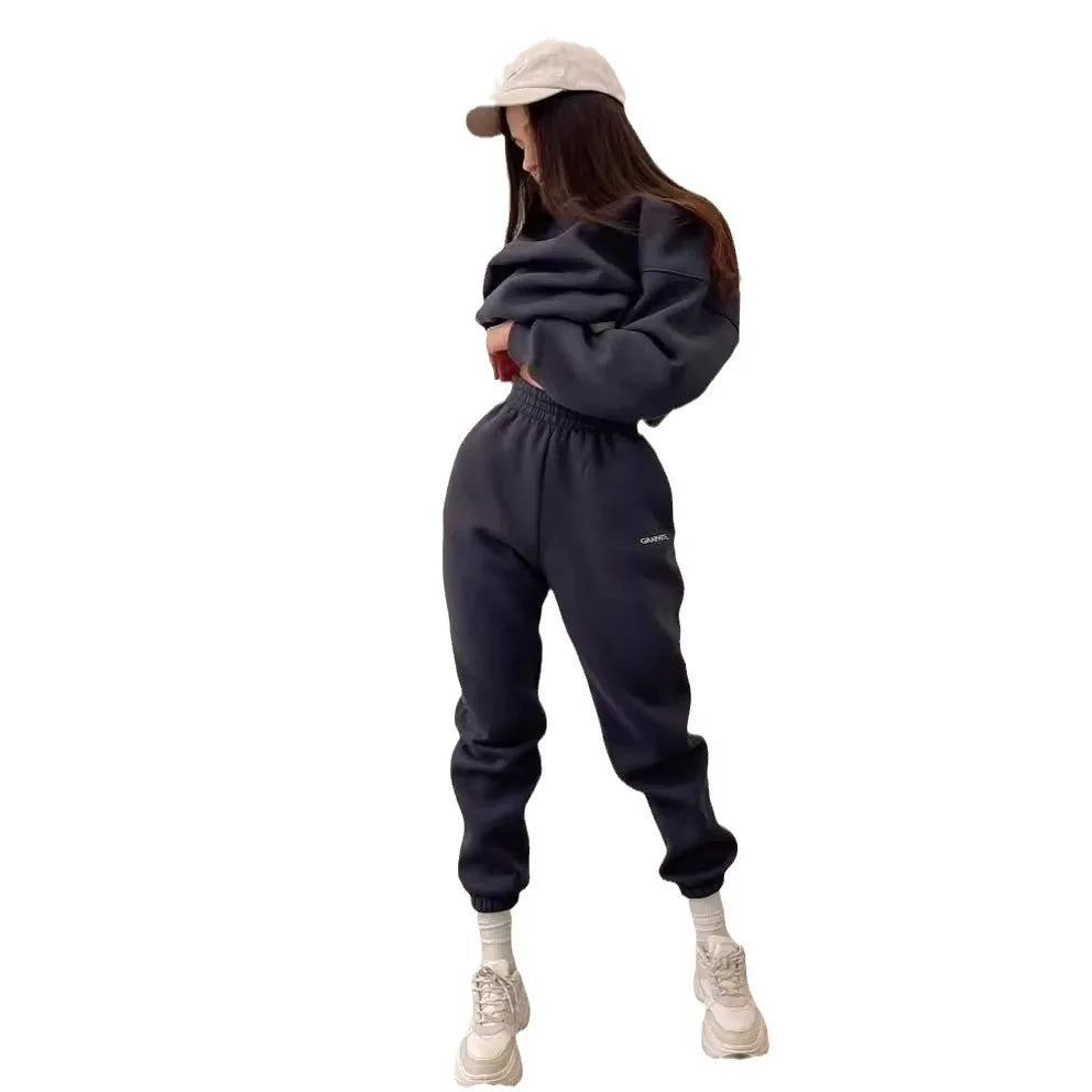 Person wearing a dark gray sweatshirt and pants with a beige cap on a white background