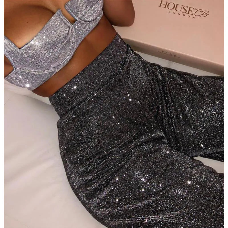 Person wearing silver glittery top and pants with 'House of CB' box in the background.