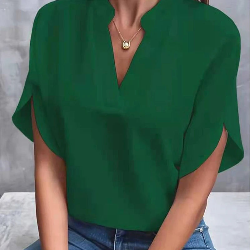 Green blouse with a deep neckline worn by a person against a neutral background