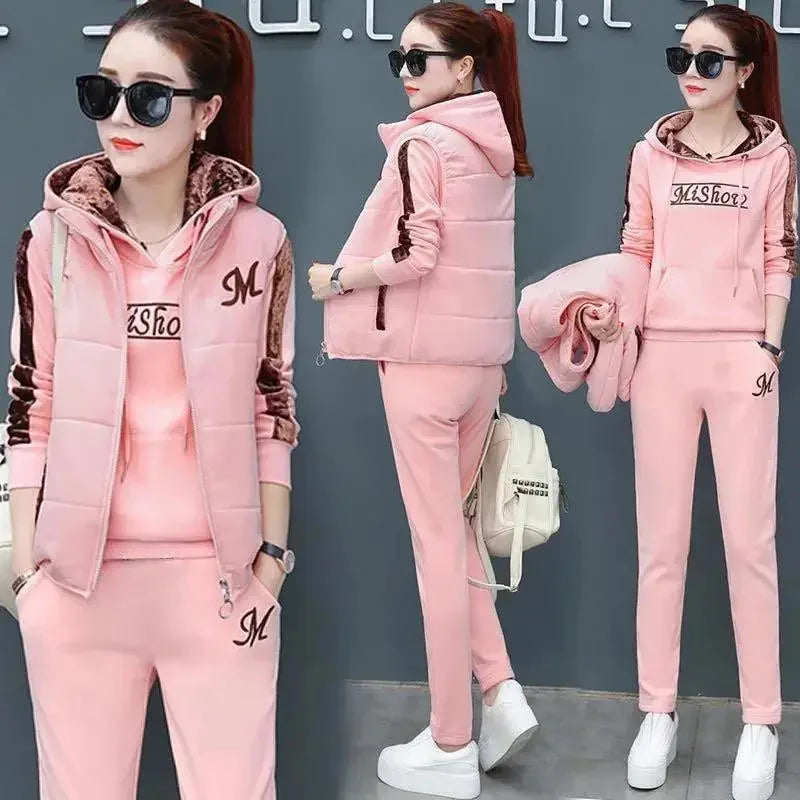 Woman wearing a pink tracksuit with a brand logo, posing against a gray background.