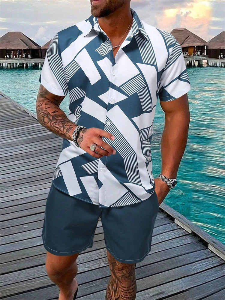 Man wearing a patterned shirt and shorts standing on a dock with water and buildings in the background