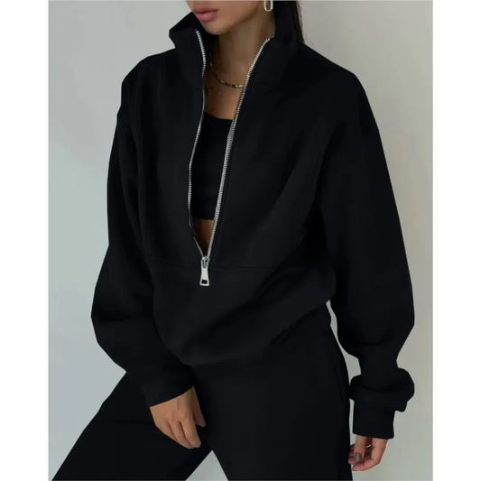 Person wearing a black zip-up hoodie against a neutral background