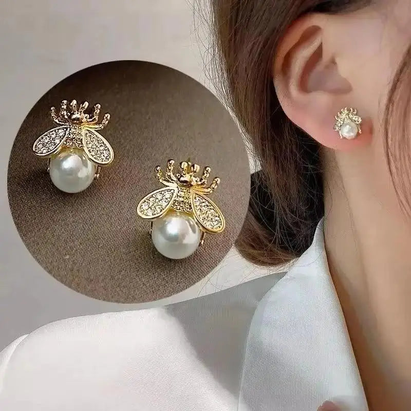 Pearl bee-shaped earrings on a woman's ear with close-up of earring on beige background
