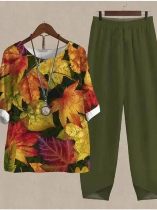 Colorful leaf-patterned shirt and green pants on hangers against a beige background