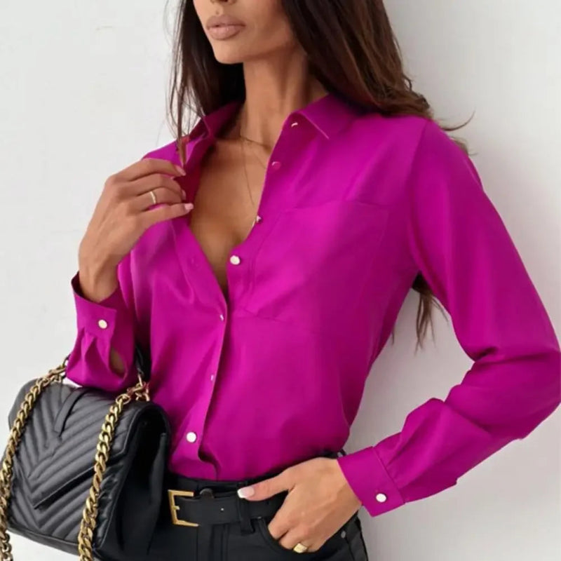 Woman wearing a bright pink blouse with a black handbag on a white background