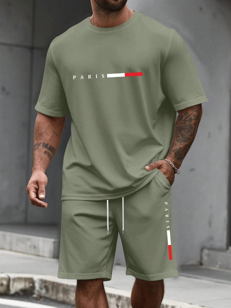 Person wearing a green 'PARIS' t-shirt and shorts set against a gray background