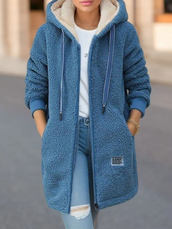 Blue fleece jacket with beige hood worn by a person on a blurred background