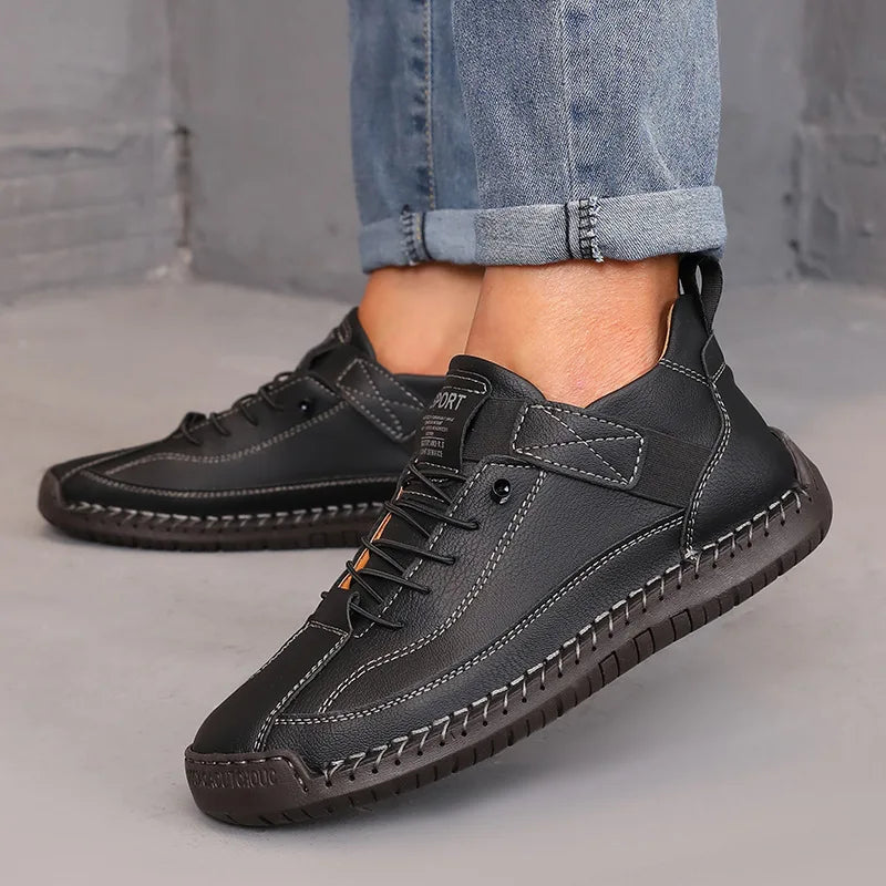 Black leather shoes worn with rolled-up jeans on a neutral background
