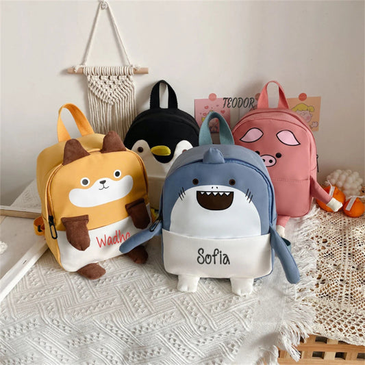 Four children's backpacks with animal designs on a textured surface.