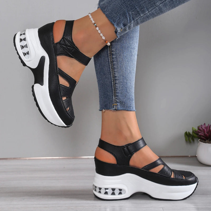 Black and white platform sandals worn with blue jeans on a neutral background