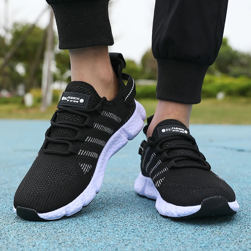 Black running shoes with white soles worn by a person on a blue surface.
