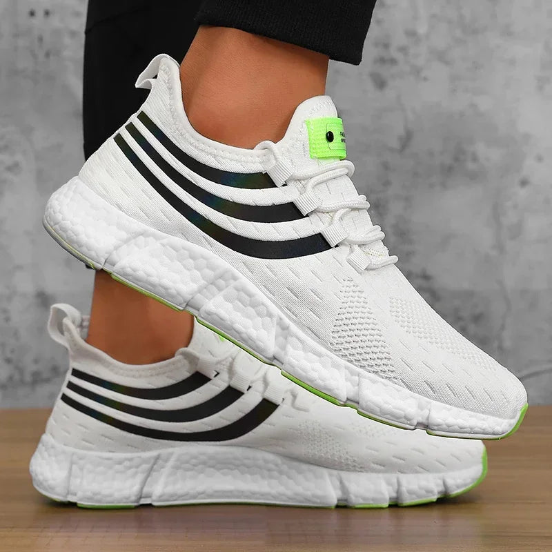 White sneakers with black stripes and green accents on a neutral background
