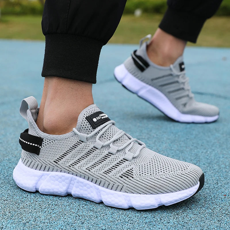 Gray athletic shoes with black accents worn on a blue surface
