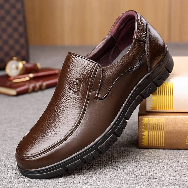 Brown leather shoe on a textured surface with books and a watch in the background