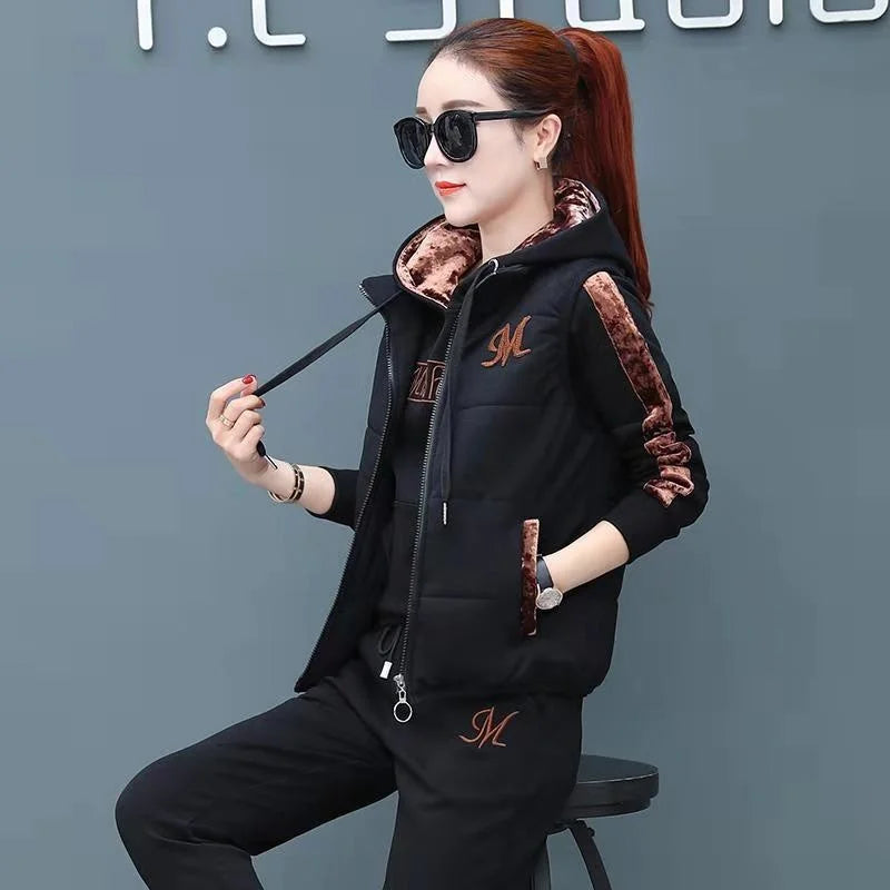 Woman wearing a black tracksuit with brown accents and sunglasses against a gray background