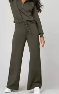 Person wearing a green outfit with wide-leg pants on a plain background